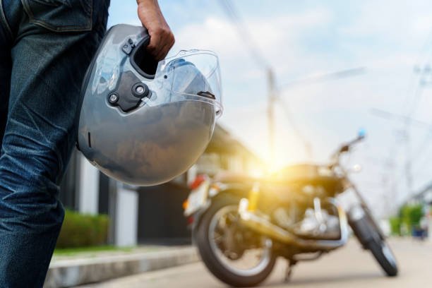 Grab your helmet and hit the road. a young man riding a motorbike through the city. Rear view of a biker in a leather jacket with a chopper holding a helmet